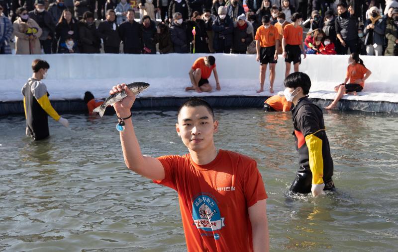Seorang pengunjung terlihat sedang berpose setelah berhasil menangkap sancheoneo dengan tangan kosong pada tanggal 9 Januari di Festival Hwacheon Sancheoneo yang digelar di Sungai Hwacheon, Hwacheon-gun, Provinsi Gangwon. (Kim Sunjoo) 