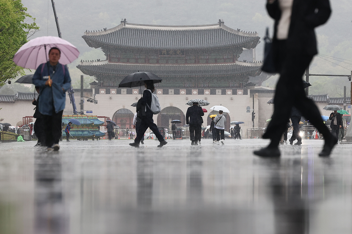Para warga terlihat sedang menggunakan payung saat berjalan di tengah Alun-alun Gwanghwamun di Seoul pada tanggal 15 April. (Yonhap News)