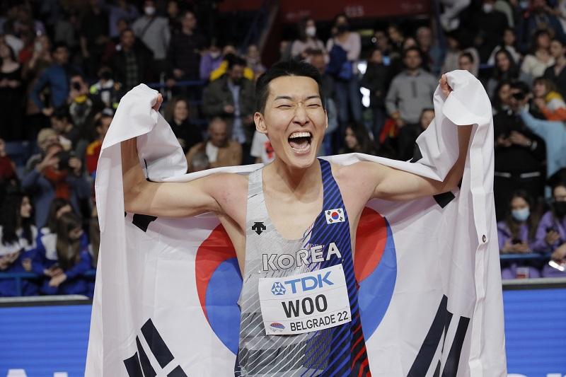 Woo Sang-hyeok terlihat gembira dengan memegang bendera negara Korea Selatan setelah memastikan dirinya mendapatkan medali emas. Woo Sang-hyeok meraih emas dengan rekor 2,34 m pada cabang olahraga lompat tinggi di Kejuaraan Dunia Atletik Dalam Ruangan pada 20 Maret (waktu setempat) di Štark Arena, Beograd, Serbia. (Yonhap News) 