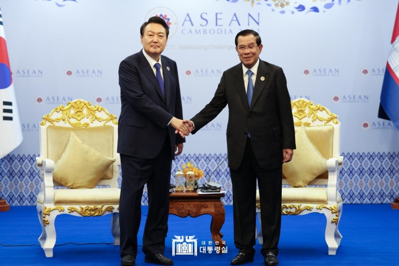 Presiden Yoon (kiri) bersalaman dengan Perdana Menteri Kamboja, Hun Sen (kanan) pada tanggal 11 November pada pertemuan yang diselenggarakan di sebuah hotel di Phnom Penh, Kamboja. Ini adalah pertemuan pertama antara kedua pemimpin setelah Presiden Yoon dilantik pada bulan Mei lalu. Presiden Yoon mengungkapkan, Semoga perdagangan dan investasi antara Korea dan Kamboja bisa menjadi semakin berkembang berkat 'kebijakan penghindaran pajak berganda' dan perjanjian perdagangan bebas (FTA).