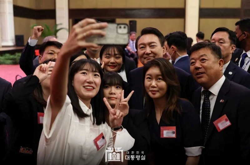 Presiden Yoon sedang berswafoto bersama warga negara Korsel yang mengikuti dialog kenegaraan pada tanggal 11 November di Hotel Sofitel, Phnom Penh, Kamboja. Pada hari tersebut, Presiden Yoon mengungkapkan rasa terima kasihnya kepada para warga negara Korsel atas kerja keras mereka dalam menjaga hubungan yang baik antara Korsel dan Kamboja. Presiden Yoon berjanji akan berusaha sebaik mungkin untuk membuat mereka bangga akan tanah air mereka.