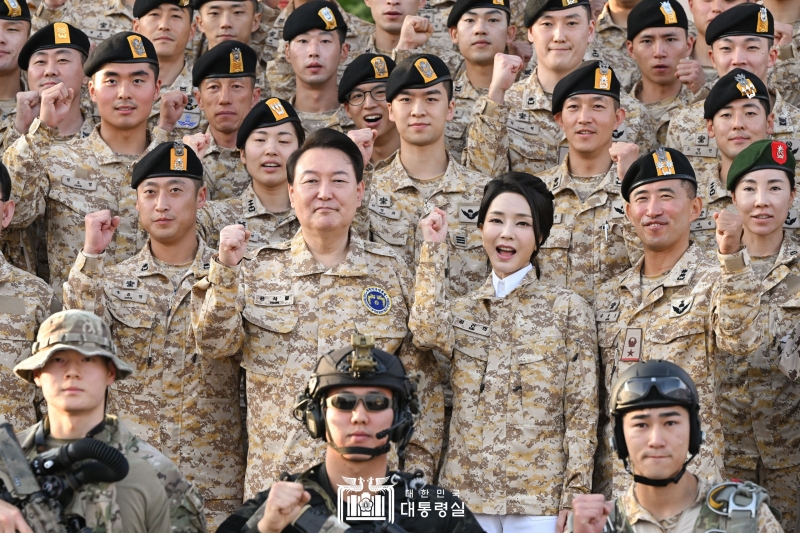  Presiden Yoon Suk Yeol (kedua dari kiri di baris kedua) dan Ibu Negara Kim Keon Hee berfoto bersama pada tanggal 15 Januari (waktu setempat) dengan para prajurit militer Korea yang beraktivitas di UAE. Kunjungan presiden ke Unit Akh ini merupakan salah satu bagian dari rangkaian kunjungan kenegaraan Presiden Yoon ke UAE. Presiden Yoon berkata, Keberadaan dan keaktifan Anda semua di sini mampu memperlihatkan kekuatan pertahanan nasional Korea ke seluruh dunia. Presiden Yoon lalu memuji para prajurit dengan berkata, Keberadaan Anda semua di sini sangat membanggakan dan membuat kami merasa kuat karena peran Anda semua sebagai pimpinan angkatan bersenjata perwakilan Korea. (Kantor Kepresidenan Republik Korea)