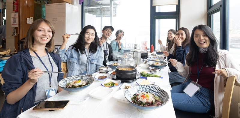 Tujuh orang wartawan kehormatan yang berasal dari berbagai negara menikmati berbagai makanan laut khas Namhae di sebuah restoran pada tanggal 24 Mei. Dari kiri ke kanan: Karina Gur dari Jerman, Anastassiya Kim dari Kazakstan, Mohammad Iqbal Jerusalem dari Indonesia, Kaori Yoshioka dari Jepang, Virginie Schultz dari Prancis, Quang Thi Thuy Dung dari Vietnam, dan Yang Huiyan dari Tiiongkok. 