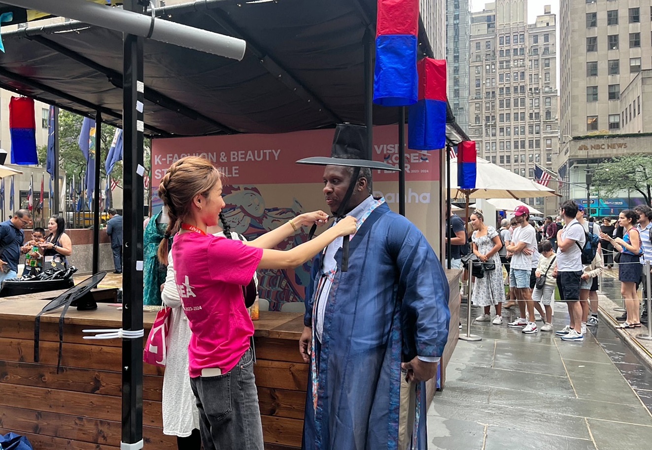 Seorang pengunjung terlihat sedang mencoba hanbok pada stan informasi pariwisata Korea yang dipasang di Rockefeller Center, New York, Amerika Serikat.