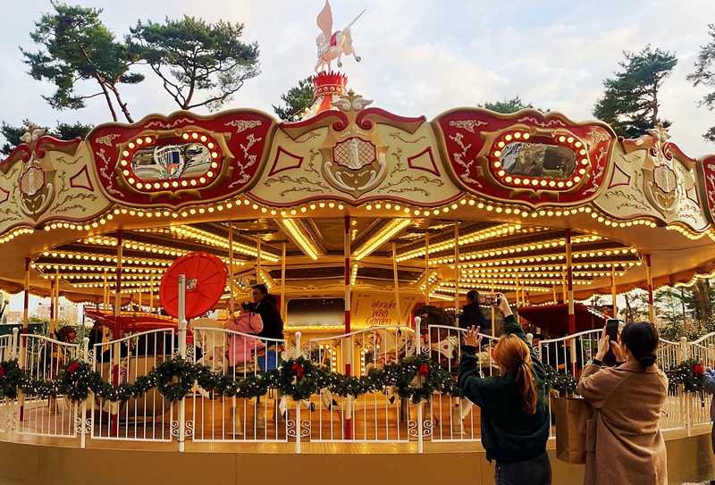 Sebuah taman Natal luar ruangan yang fantastis dibuat di Lotte World Jamsil yang terletak di Songpa-gu, Seoul. Sebuah pohon Natal raksasa setinggi 19 meter dapat ditemui oleh para pengunjung setelah melewati pintu labirin di bagian ujung taman. Selain itu, terdapat juga komidi putar yang bisa dinaiki oleh para pengunjung. (Lee Da Som)