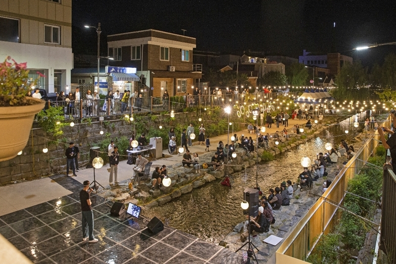 Kota Gongju yang terletak di Provinsi Chungcheongnam terpilih sebagai kota yang memiliki spesialisasi dalam pariwisata malam. Foto di atas menunjukkan para wisatawan yang sedang menikmati pertunjukan busking yang digelar sebagai bagian dari 2023 Gongju Culture Night pada tanggal 8 September s/d 18 Oktober 2023 di Aliran Jemicheon, Kota Gongju. 