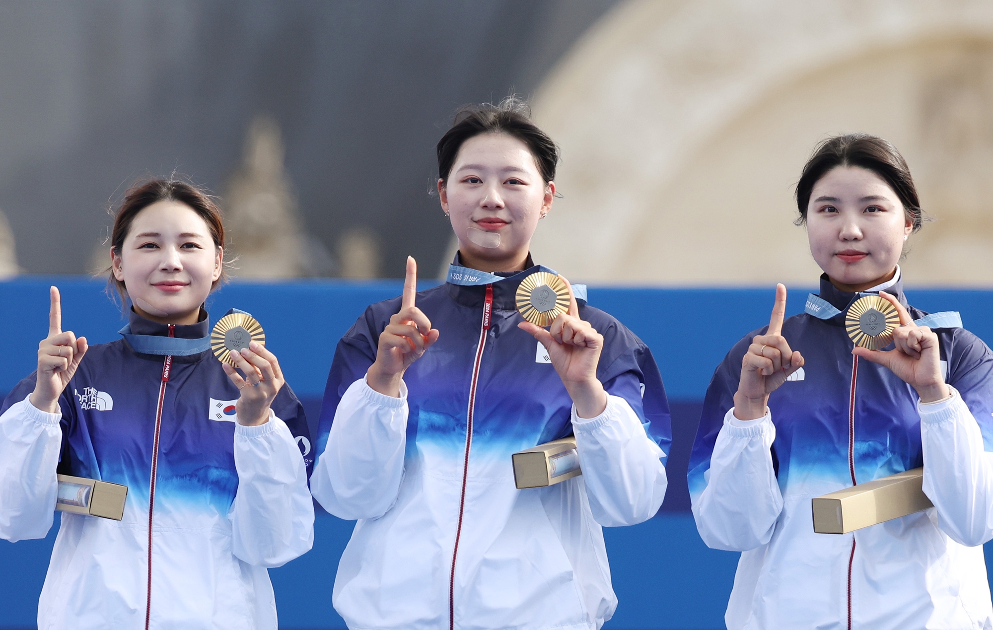 Jeon Hunyoung (kiri), Lim Sihyeon (tengah), dan Nam Suhyeon membuat angka 10 dengan jari tangan dan medali emas mereka setelah meraih medali emas kesepuluh Korea di perhelatan olimpiade untuk panahan beregu putri pada tanggal 28 Juli 2024 (waktu setempat) di Paris, Prancis.  