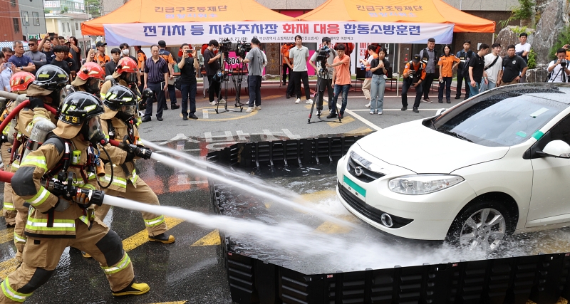 Para petugas pemadam kebakaran terlihat sedang melakukan pelatihan pemadaman kebakaran pada tanggal 27 Agustus 2024 di lahan parkir Apartemen Raemian Urban Park, Busanjin-gu, Busan. Pelatihan gabungan tersebut merupakan pelatihan tanggapan darurat untuk mobil listrik yang terbakar dan para pemadam kebakaran menggunakan tangki air bergerak untuk mencoba memadamkan mobil listrik yang terbakar. (Yonhap News) 