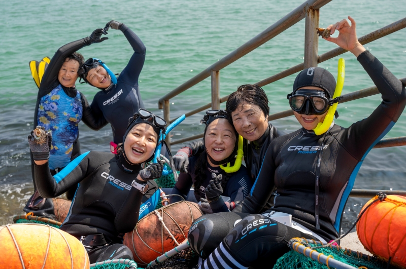 Para peserta program aktivitas bersama haenyeo terlihat sedang berfoto bersama dengan haenyeo yang mengajar mereka untuk menyelam dan mencari hewan laut pada tanggal 8 September 2024 di Desa Sehwa, Gujwa-eup, Kota Jeju. (Kim Da Eun)  