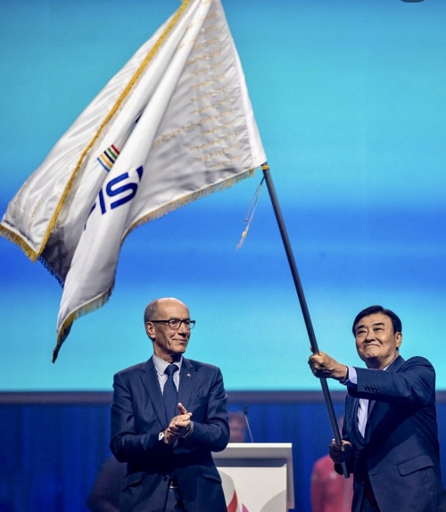 Ketua Komite Penyelenggara 2027 Chungcheong Universiade, Kang Chang-hee, terlihat sedang mengibarkan bendera setelah serah terima tuan rumah penyelenggara yang digelar pada upacara penutupan Rhine-Ruhr 2025 tanggal 27 Juli 2025 (waktu setempat) di Duisburg, Jerman. (media sosial FISU)  