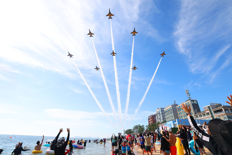 Para pengunjung Festival Lumpur Boryeong terlihat menikmati pertunjukan udara yang meriah dari Tim Akrobatik Angkatan Udara Republik Korea, Black Eagles.  