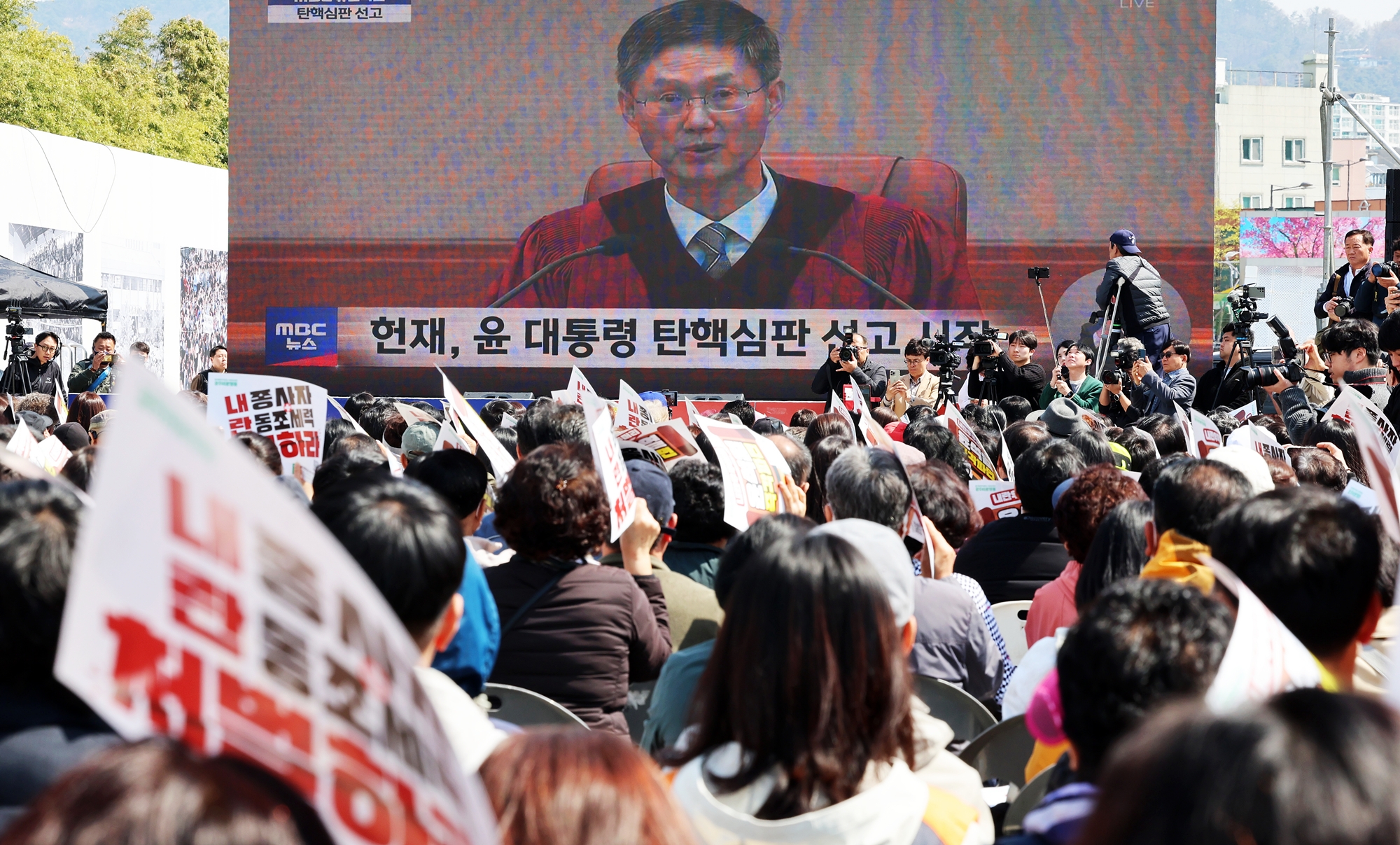 Pemakzulan mantan Presiden Yoon Suk Yeol diputuskan melalui sidang yang digelar pada tanggal 4 April 2025. Mahkamah Konstitusi Korea membacakan keputusan untuk memberhentikan mantan Presiden Yoon dari jabatannya melalui suara bulat delapan hakim MK untuk penyetujuan mosi pemakzulan dari Majelis Nasional. Mantan Presiden Yoon menetapkan status darurat militer pada tanggal 3 Desember 2024 dan Majelis Nasional mengeluarkan mosi pemakzulan pada tanggal 14 Desember 2024.Foto di atas memperlihatkan warga yang sedang menonton siaran langsung sidang putusan Mahkamah Konstitusi terhadap mantan Presiden Yoon pada tanggal 4 April 2025 di Alun-alun Demokrasi 18 Mei, Dong-gu, Gwangju. (Yonhap News)  
