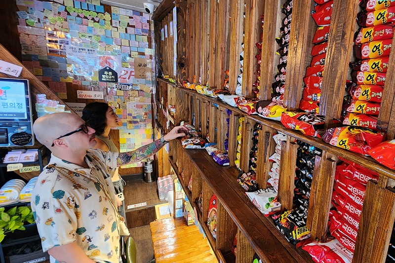 Foto di atas menunjukkan dua orang wisatawan asing yang sedang memilih ramyeon di sebuah minimarket, Seoul pada tanggal 6 Agustus 2025. (Yonhap News)