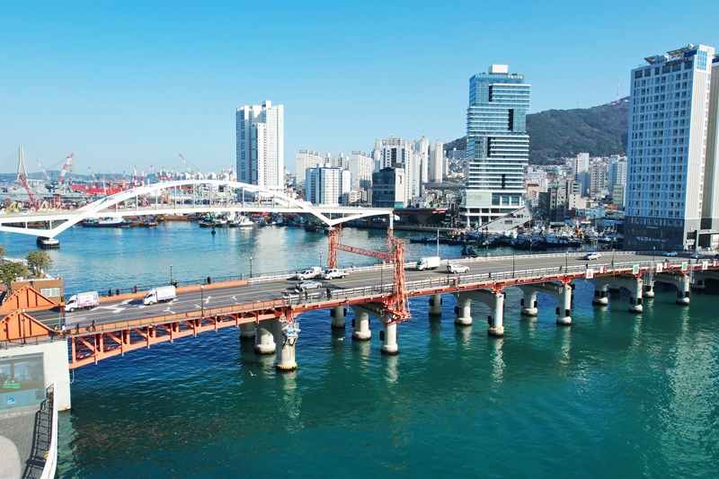 Foto di atas menunjukkan Jembatan Yeongdodaegyo (depan) dan Busandaegyo yang menyambungkan Kota Busan dengan Pulau Yeongdo. Alun-alun pengungsi yang berada di dekat Jembatan Yeongdo saat ini berfungsi menjadi ruang peringatan untuk mengenang sosok Busan pada masa Perang Korea.  