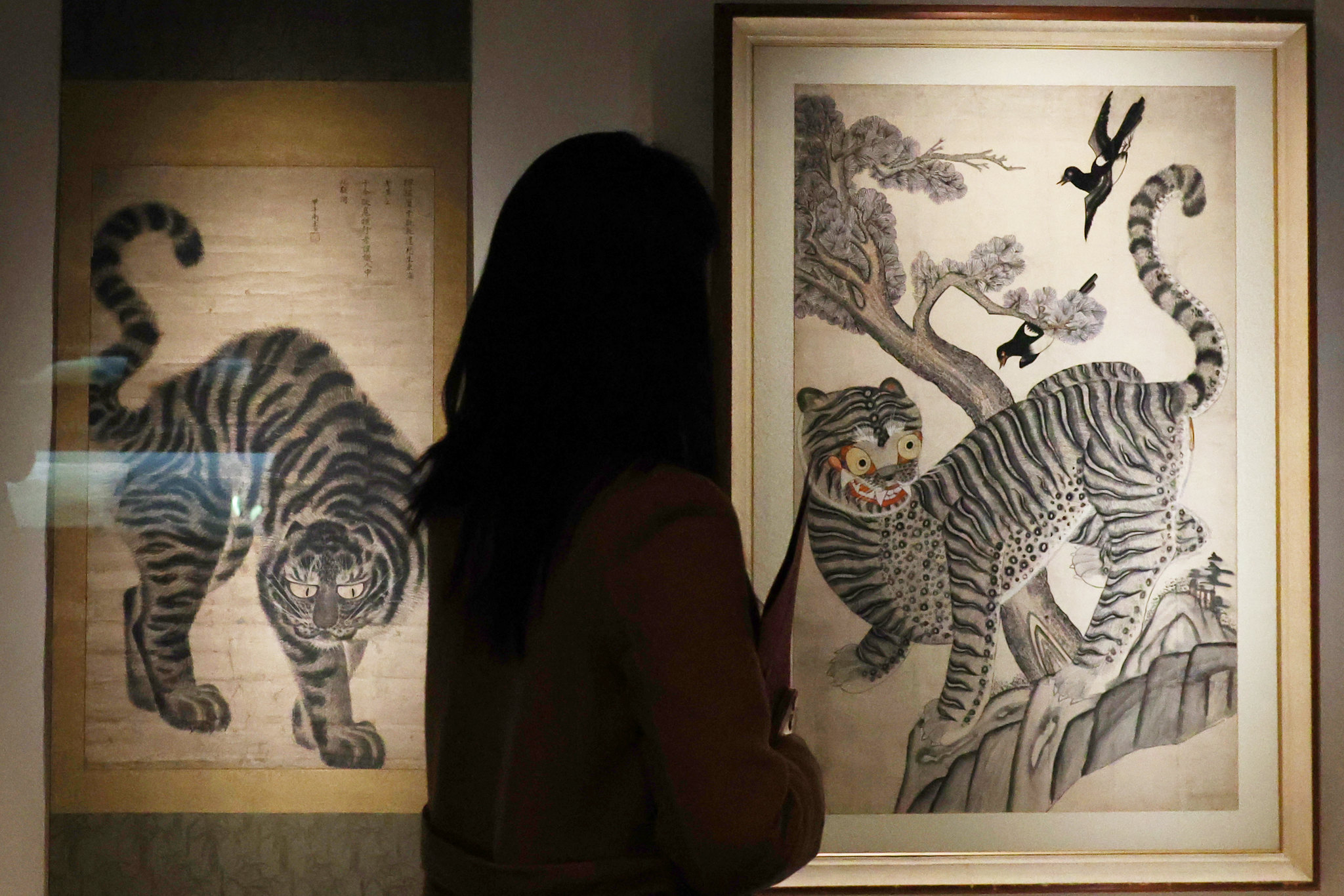 Seorang wartawan sedang memperhatikan lukisan tradisional yang menggambarkan harimau dengan burung kucica Korea pada tanggal 25 Februari 2026 di Museum Nasional Korea, Yongsan-gu, Seoul. (Lee Jeong Woo)  