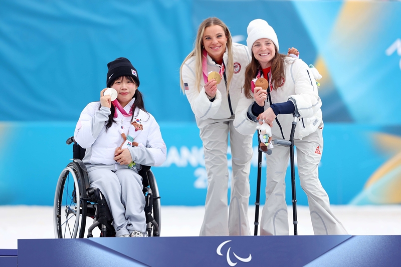 Kim Yunji (kiri) berfoto bersama Masters Oksana (tengah) dan Gretsch Kendall (kanan) di atas podium setelah menyelesaikan pertandingan para ski lintas alam nomor 10 km interval start duduk putri yang digelar pada tanggal 11 Maret 2026 (waktu setempat) di Stadion Tesero Cross-Country, Italia.  