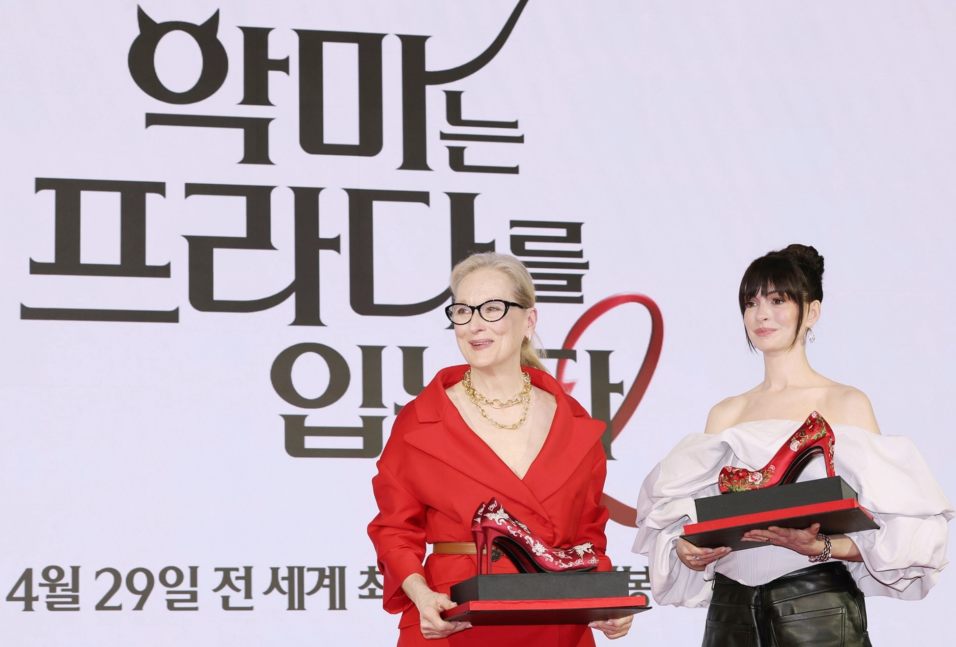 Meryl Streep (kiri) dan Anne Hathaway berpose dengan membawa sepatu berhak tinggi dengan motif tradisional Korea dalam konferensi pers The Devil Wears Prada 2 yang digelar pada tanggal 8 April 2026 di Hotel Four Seasons, Jongno-gu, Seoul. (Lee Jeong Woo)  