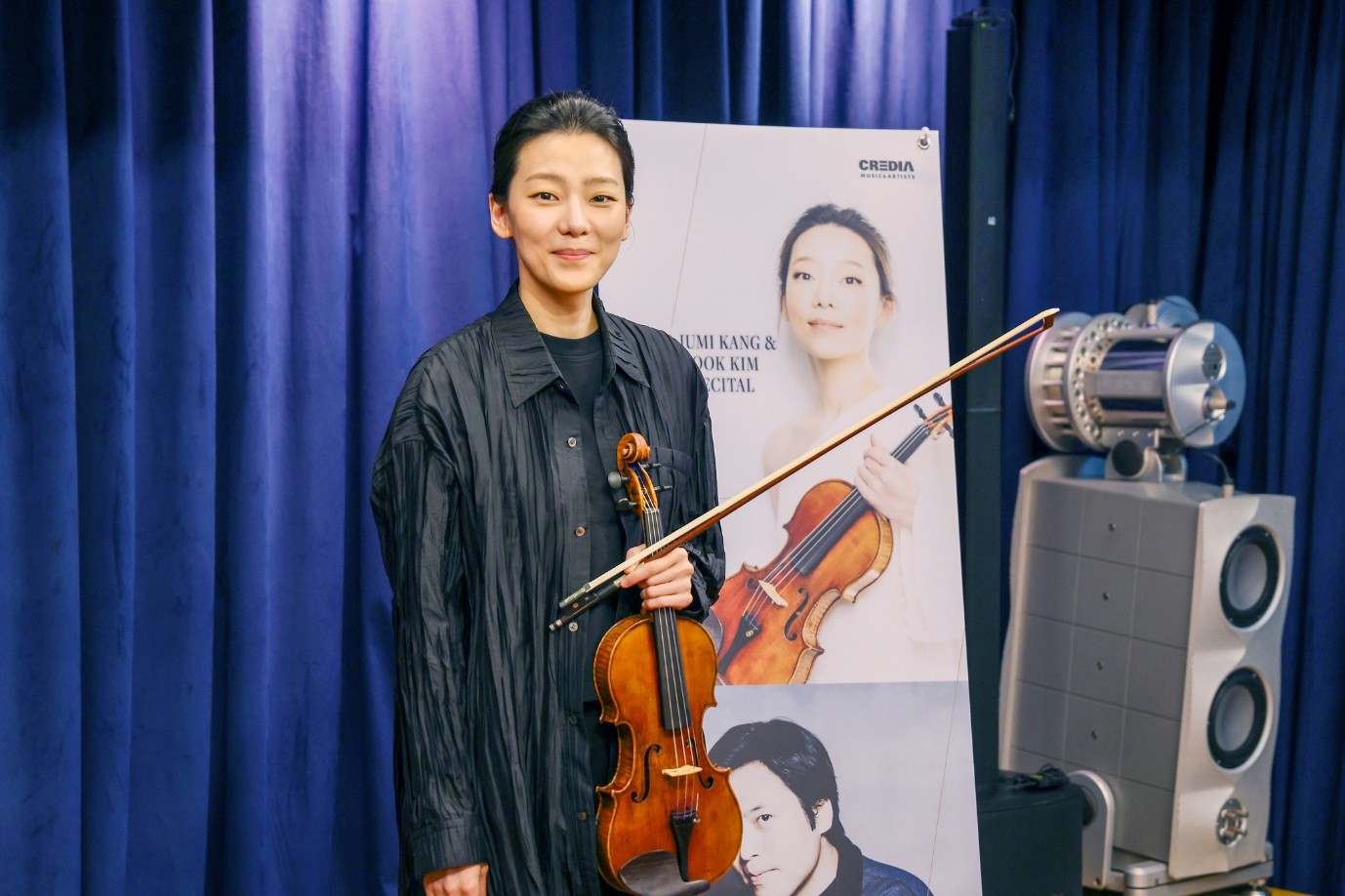 Pada tanggal 7 Mei 2026 violinis Clara-Jumi Kang terlihat sedang berpose ke arah awak media dalam konferensi pers yang digelar di Studio Credia Classic Club, Jongno-gu, Seoul.