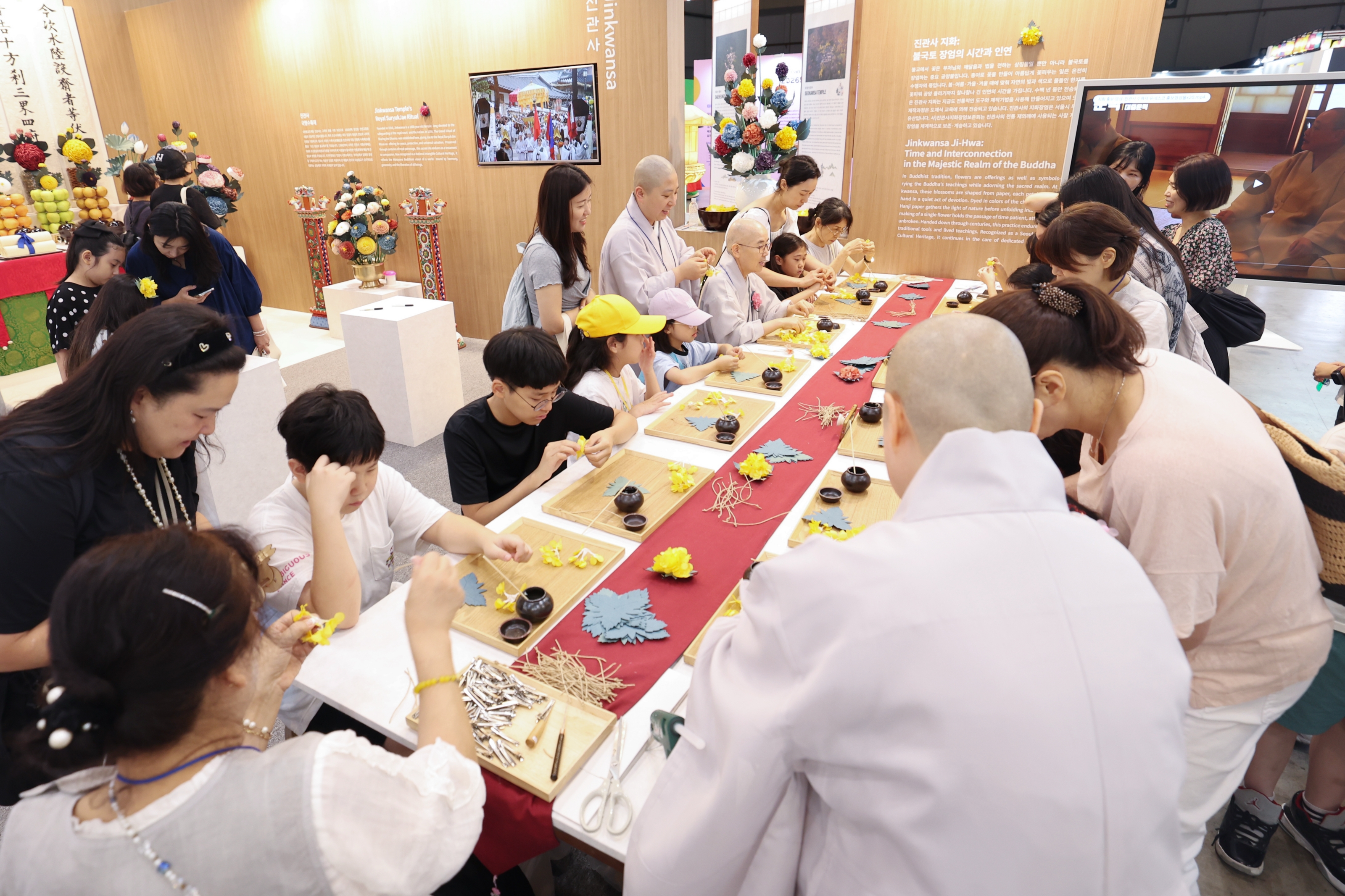 Para pengunjung terlihat mengikuti program membuat bunga tradisional kertas pada tanggal 23 Juli 2026 di stan Kuil Jingwansa di K-Heritage House, BEXCO, Haeundae-gu, Busan.  