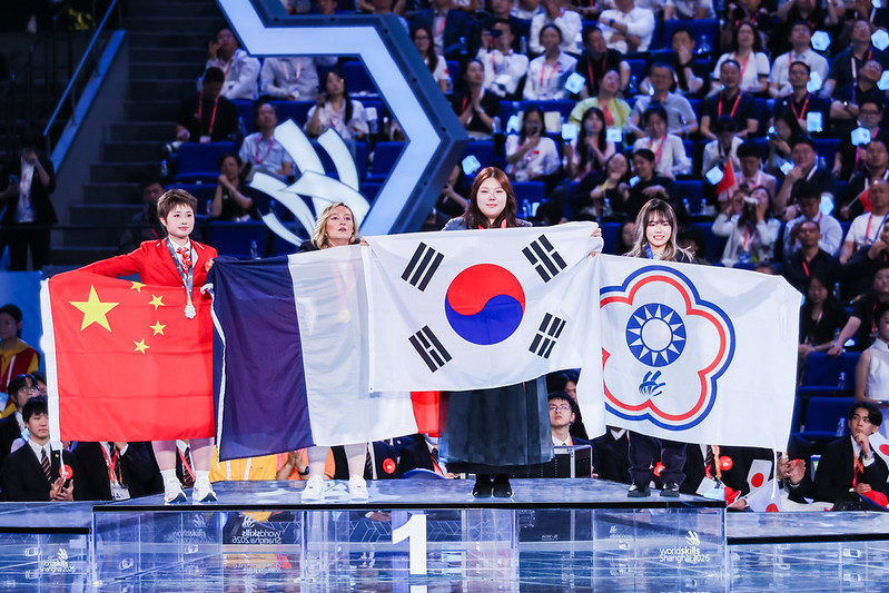 Kim Jo Yeong, peraih medali emas dalam cabang tata rambut, merayakan kemenangannya sambil memegang bendera Korea dalam upacara penutupan WorldSkills Shanghai 2026 pada tanggal 27 September 2026 di Shanghai World Expo Cultural Center, Tiongkok. (WorldSkills International)  