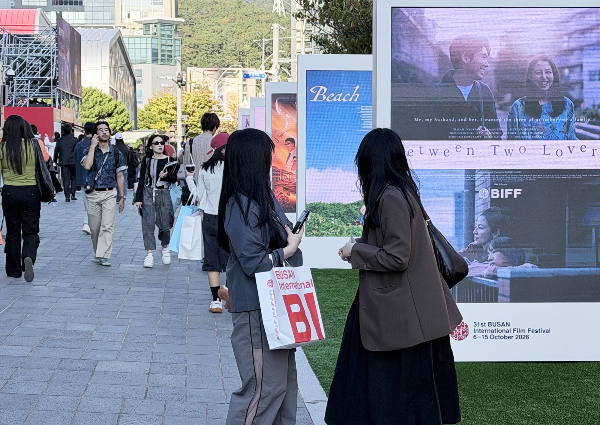Para pengunjung Festival Film Internasional Busan ke-31 berjalan sambil melihat layar elektronik yang menampilkan informasi film pada tanggal 7 Oktober 2026 di Busan Cinema Center, Haeundae-gu, Busan. (Xu Aiying)