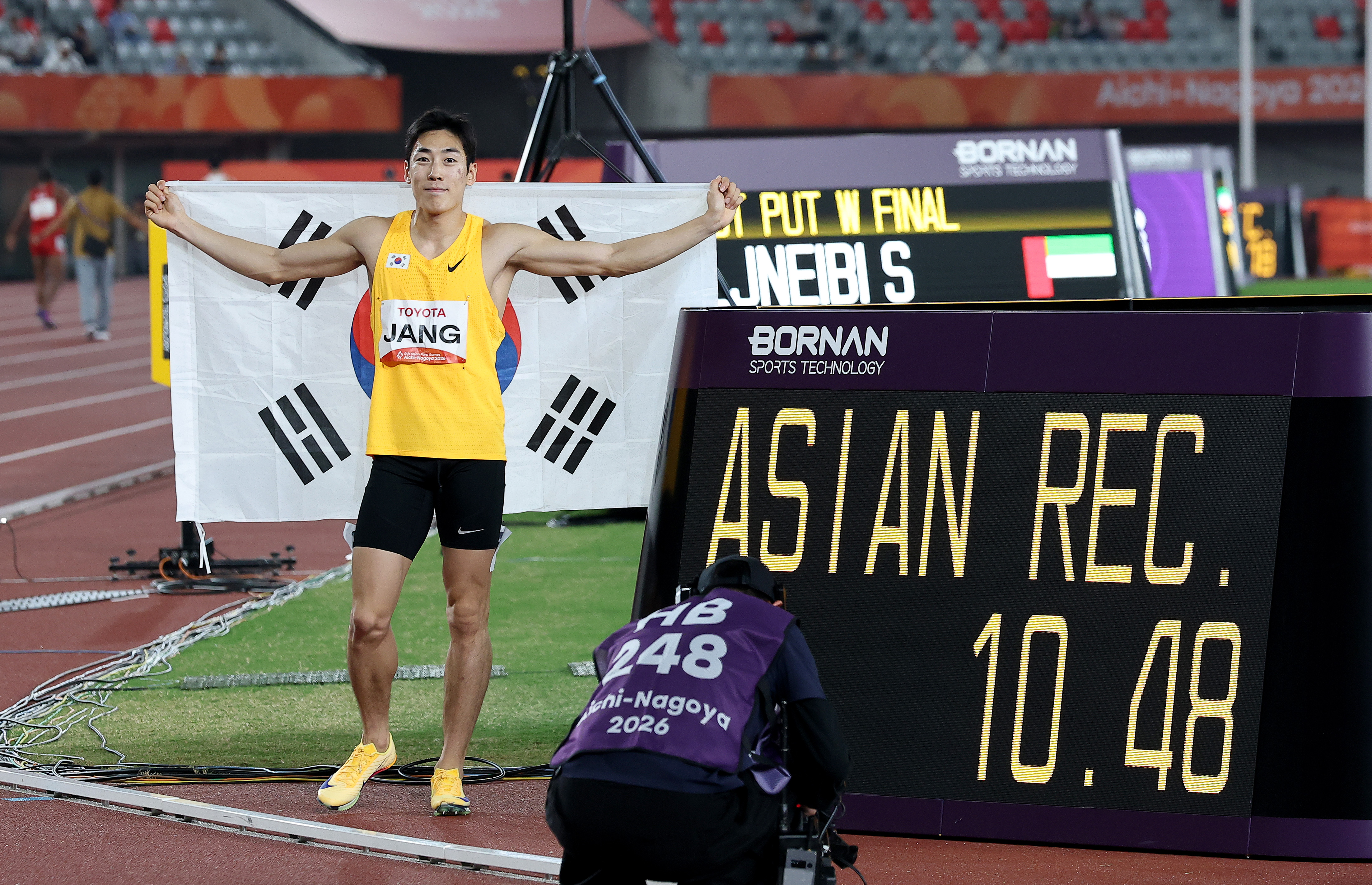Jang Minho berfoto di samping papan catatan waktu setelah meraih medali emas dalam final lari 100 meter putra (T13) Asian Para Games Aichi-Nagoya 2026 pada tanggal 20 Oktober 2026 di Stadion Atletik Taman Mizuho, Kota Nagoya,Jepang. Ia mencetak rekor Asia dengan waktu 10,48 detik.