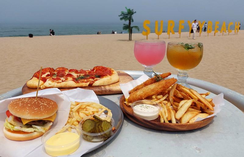 Pengunjung bisa merasakan suasana seperti di luar Korea di sunset bar yang terletak di Pantai Surfyy. Ada berbagai makanan dan minuman yang bisa dinikmati di sini, seperti piza, hamburger, dan fish and chips. (Anais Faure) 