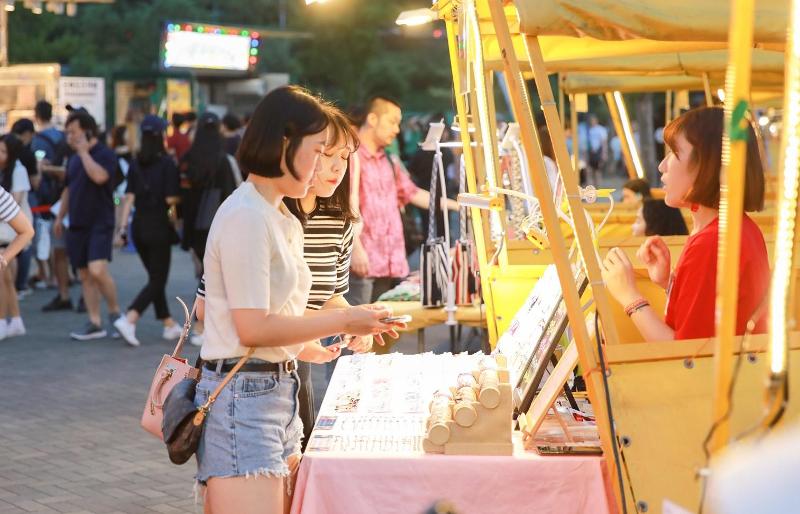 Orang-orang melihat-lihat barang-barang di stan penjualan di pasar malam sungai Han yang dibuka pada tahun 2019