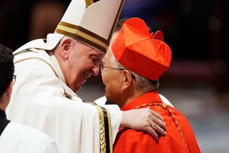 Paus Fransiskus memeluk Kardinal Lazarus You Heung-sik pada upacara pelantikannya di Basilika Santo Petrus. Kardinal You terlihat memakai topi biretta berwarna merah yang melambangkan gelarnya sebagai seorang kardinal. (Yonhap News)