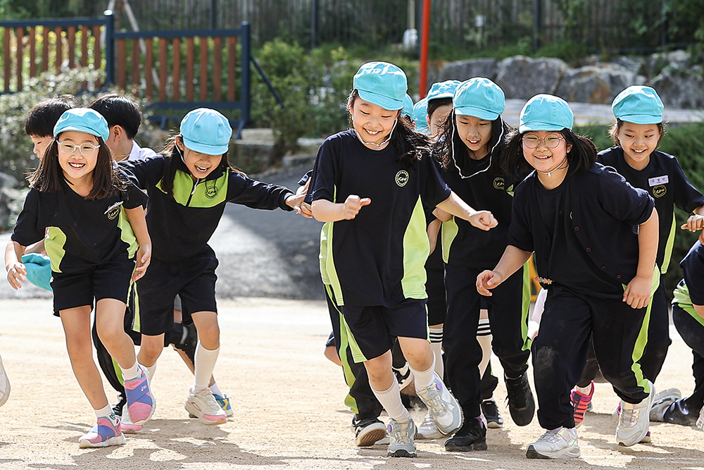 Anak-anak yang melepas masker berlari di sebuah sekolah dasar di Seoul pada tanggal 26 September ketika kewajiban untuk memakai masker di luar ruangan benar-benar dicabut. (Yonhap News)