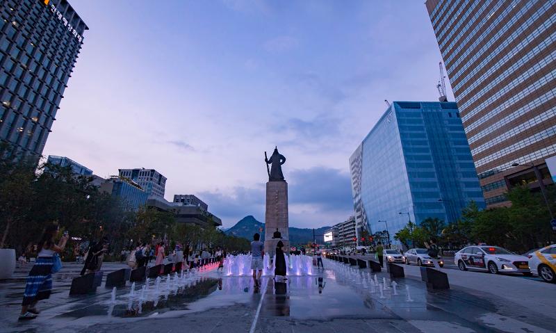 Warga yang mengunjungi Alun-alun Gwanghwamun di Seoul bersenang-senang di air mancur yang berada di depan patung Yi Sun-sin. 