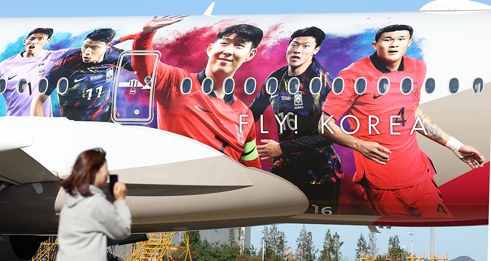 Sebuah pesawat yang menampilkan gambar lima anggota tim sepak bola nasional pada 17 Oktober diparkir di gerbang Asiana Airlines di Bandara Internasional Incheon. Untuk mempromosikan tim, pesawat akan beroperasi selama tiga bulan hingga Desember di rute domestik, Eropa, Amerika, dan Asia Timur. Dari kiri ke kanan adalah Kim Seung-gyu, Hwang Hee-chan, Son Heung-min, Hwang Ui-jo dan Kim Min-jae. 