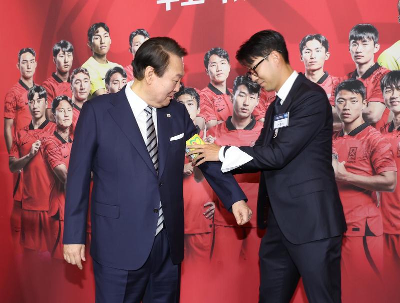 Son Heung-min (kanan) memakaikan ban lengan kapten timnas kepada Presiden Yoon pada jamuan makan malam timnas Korea yang diselenggarakan pada tanggal 8 Desember di Yeonbingwan, Cheong Wa Dae. (Yonhap News)