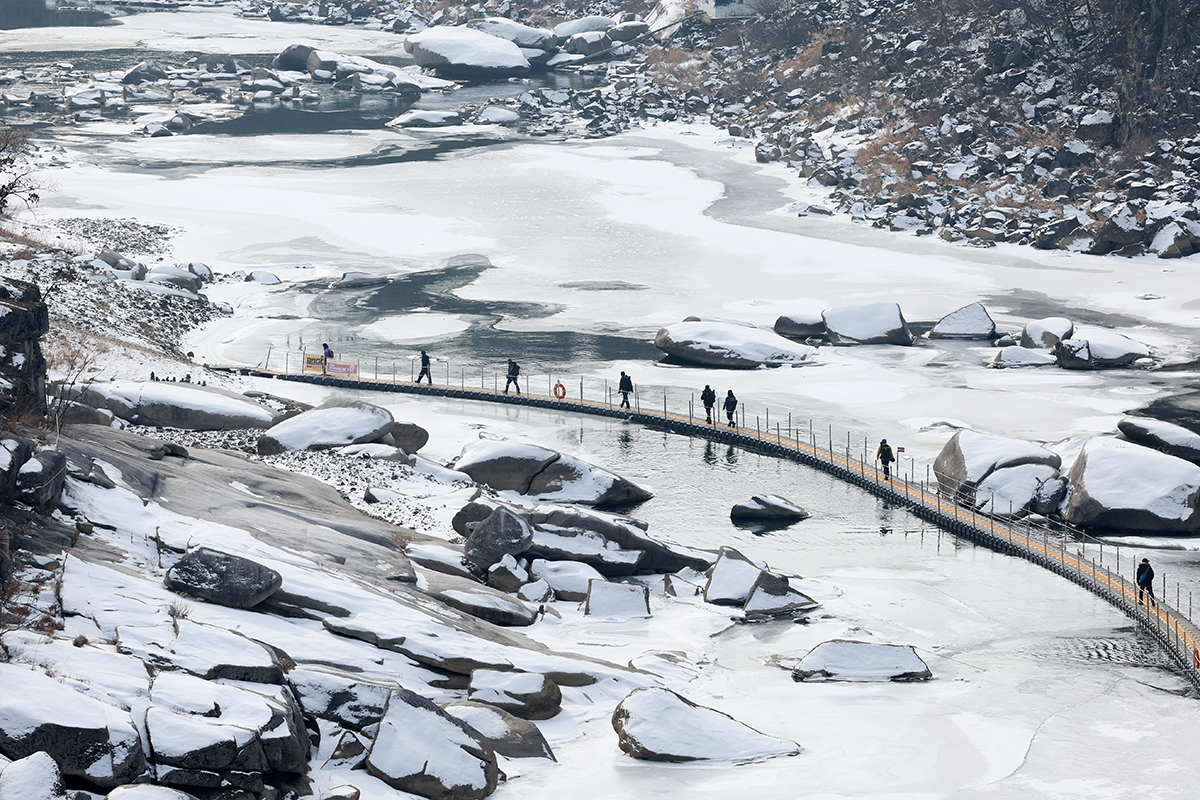 Para pengunjung yang berpartisipasi dalam Trekking Es Sungai Hantan Cheorwon 2023 berjalan di atas jembatan di atas sungai yang membeku pada tanggal 19 Januari. Festival ini diadakan di kawasan Sungai Hantangang di Cheorwon-gun, Gangwon-do (Yonhap News)