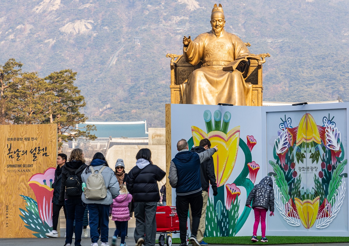 Para pengunjung berjalan melewati lukisan bunga yang dipasang sebagai bagian dari pameran musiman bertajuk Springtime Delight di Alun-alun Gwanghwamun di Distrik Jongno-gu, Seoul pada tanggal 17 Februari. (Yonhap News)<