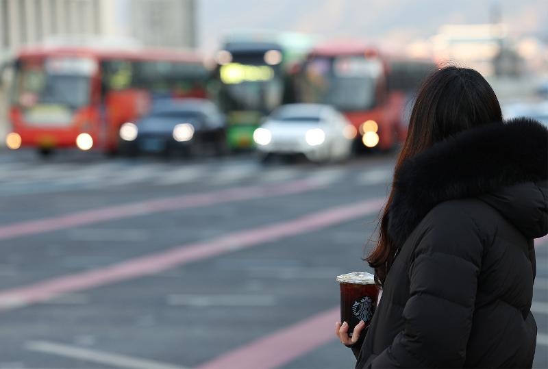 Seorang warga terlihat sedang menunggu lampu merah sambil memegang amerikano dingin pada tanggal 16 Februari di Jongno-gu, Seoul. Suhu terendah pada pagi hari saat foto diambil adalah -11 derajat Celcius. (Yonhap News)