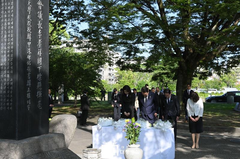 Pemimpin Korea dan Jepang berdoa bersama di depan tugu peringatan korban-korban bom atom yang berasal dari Korea. Tugu peringatan tersebut berada di Taman Perdamaian Hiroshima. Dari kiri ke kanan di barisan depan: Ibu Negara Kim Keon Hee, Presiden Yoon Suk Yeol, Perdana Menteri Jepang Fumio Kishida, dan Ibu Yuko Kishida. 