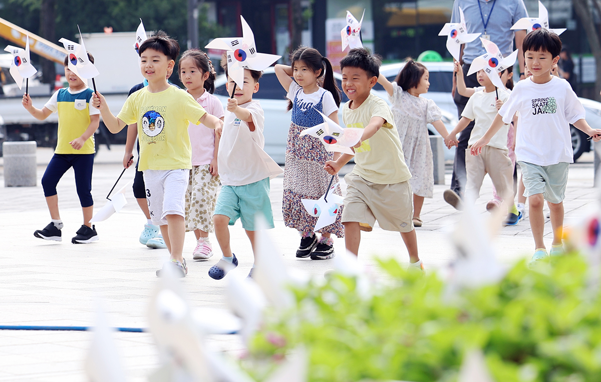 Pada tanggal 14 Agustus, anak-anak dari Tempat Penitipan Anak Kantor Buk-gu berlari dengan mainan kincir angin yang berpola Taegeukgi di Alun-alun Kantor Buk-gu, Gwangju. 15 Agustus merupakan Hari Kemerdekaan Korea yang ke-78. (Yonhap News)
