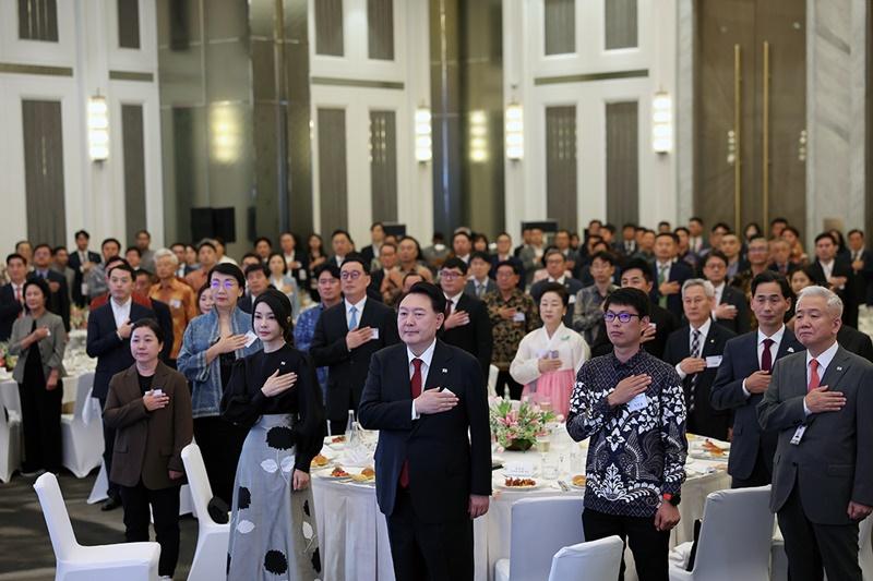 Presiden Yoon Suk Yeol (ketiga dari kanan), Ibu Negara Kim Keon Hee (kedua dari kiri), dan anggota komunitas Korea yang hadir memberikan hormat pada saat mendengarkan lagu kebangsaan Korea diputar pada jamuan makan malam dengan komunitas Korea di Indonesia yang digelar pada tanggal 5 September di sebuah hotel yang berada di Kota Jakarta, Indonesia. (Jeon Han) 