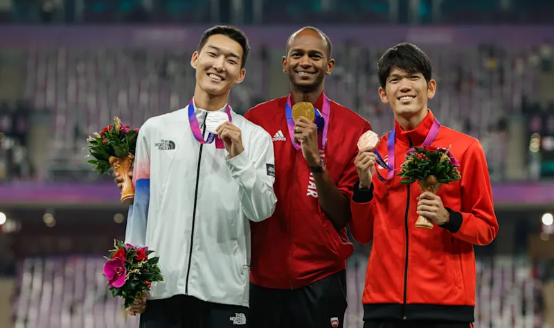 Woo Sanghyeok tersenyum sambil mengangkat medali perak pada upacara penghargaan final lompat tinggi putra Asian Games Hangzhou yang diadakan pada tanggal 4 Oktober (waktu setempat) di stadion di Hongzhou Olympic Sports Center, Tiongkok. Dari kiri ke kanan: Woo Sanghyeok, Mutaz Essa Barshim, dan Tomohiro Shinno.