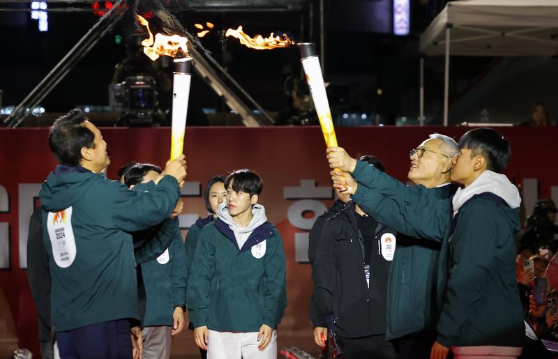 Yu In-chon (Menteri Kebudayaan, Olahraga, dan Pariwisata) menerima api dari obor Oh Se-hoon (Wali Kota Seoul) pada acara hitung mundur 100 hari jelang Olimpiade Remaja Musim Dingin Gangwon 2024 yang digelar pada tanggal 11 Oktober di Seoul Plaza, Jung-gu, Seoul. 