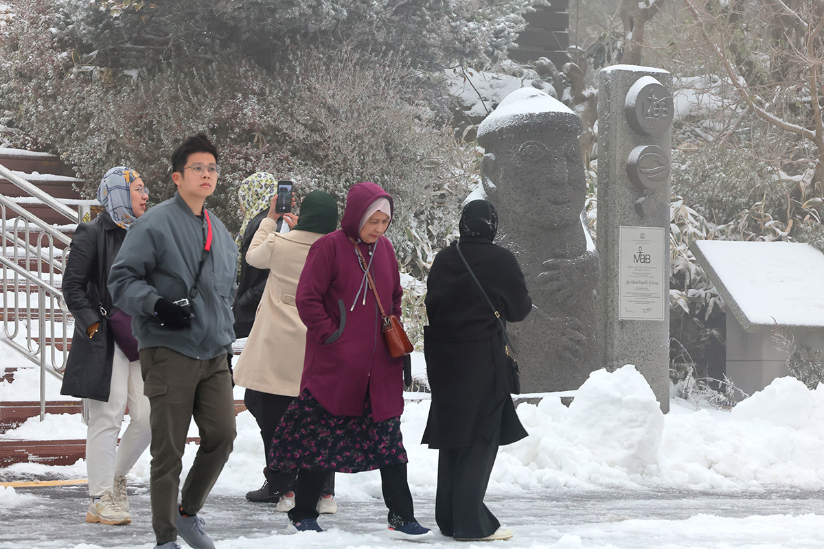 Para wisatawan asing yang mengunjungi Taman Nasional Hallasan di Jeju terlihat sedang menikmati suasana musim dingin pada pagi hari tanggal 13 November saat peringatan salju tebal dicabut. Menurut Badan Meteorologi Regional Jeju, hingga pukul 6 pagi hari ini, salju setebal 10,7 cm telah menumpuk di Puncak Samgakbong di Gunung Hallasan. (Yonhap News)