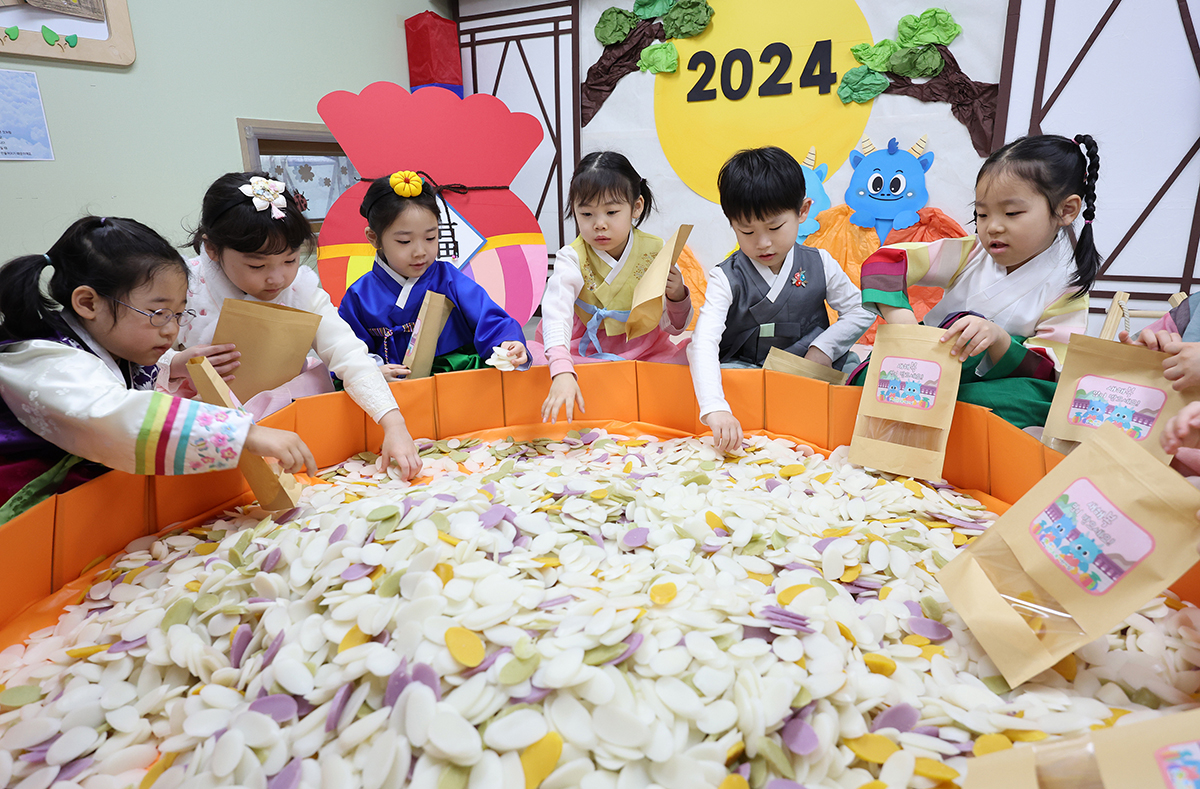 Pada pagi hari tanggal 5 Februari, anak-anak yang mengenakan hanbok sedang memasukkan kue beras ke dalam kantong kertas di Tempat Penitipan Anak Samjeon Chorok, Songpa-gu, Seoul. 5 Februari merupakan empat hari sebelum dimulainya libur hari raya Seollal (tahun baru lunar). (Yonhap News)