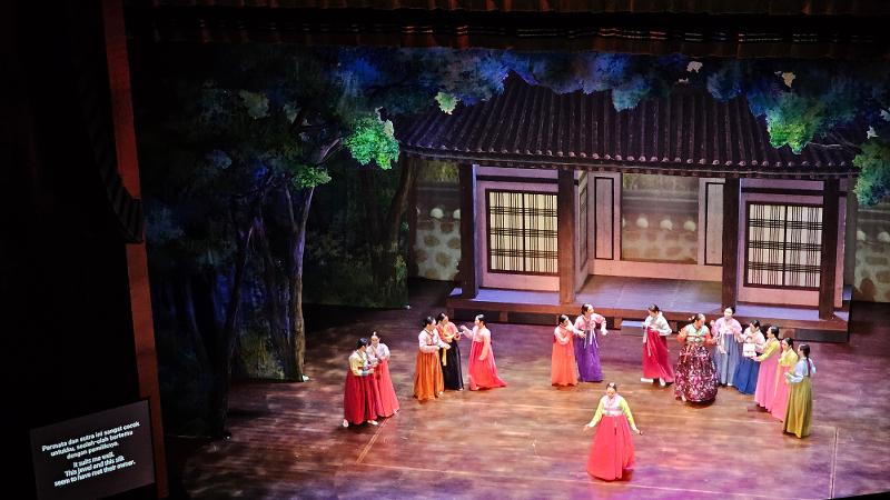 Adegan pertama dalam babak pertama opera Hari Pernikahan menampilkan tokoh utama dan para ensambel wanita berpakaian hanbok yang disertai dengan takarir dalam bahasa Indonesia dan Inggris di sisi kanan kiri panggung. 