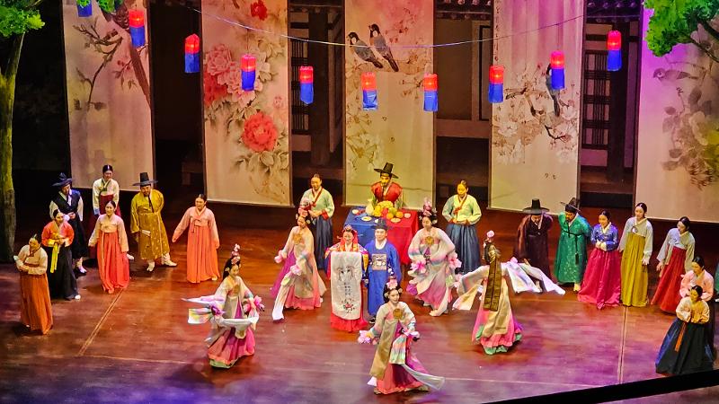 Adegan upacara pernikahan yang dikemas dengan tarian, lagu, dan kostum warna warni khas Korea. 