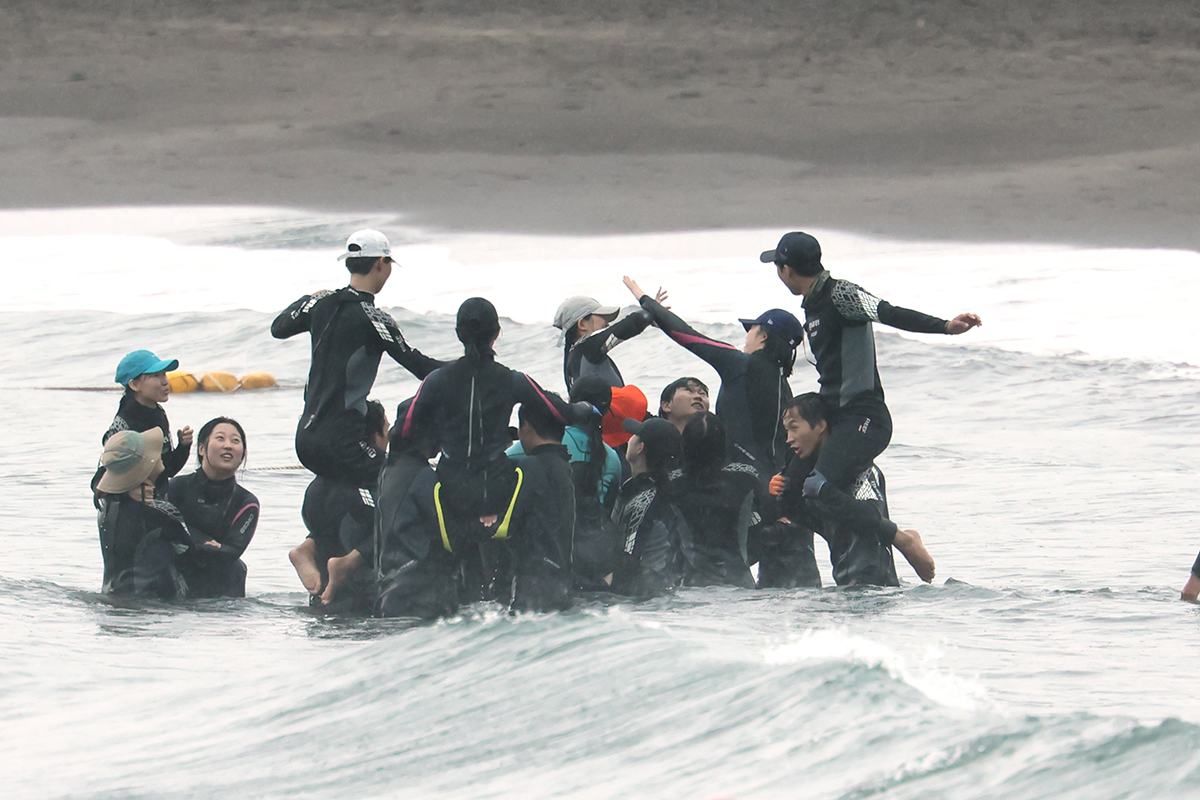 Para pengunjung Pantai Pasir Hitam Samyang di Pulau Jeju terlihat sedang menikmati ombak di tengah musim panas pada hari pembukaan Festival Pasir Hitam Samyang yang jatuh pada tanggal 19 Juli 2024. (Yonhap News)