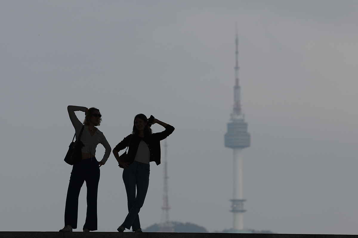 Pada tanggal 28 Oktober 2024 dua orang wisatawan asing terlihat sedang mengambil foto dengan latar belakang Menara Namsan di Museum Nasional Korea, Yongsan-gu, Seoul. (Yonhap News)