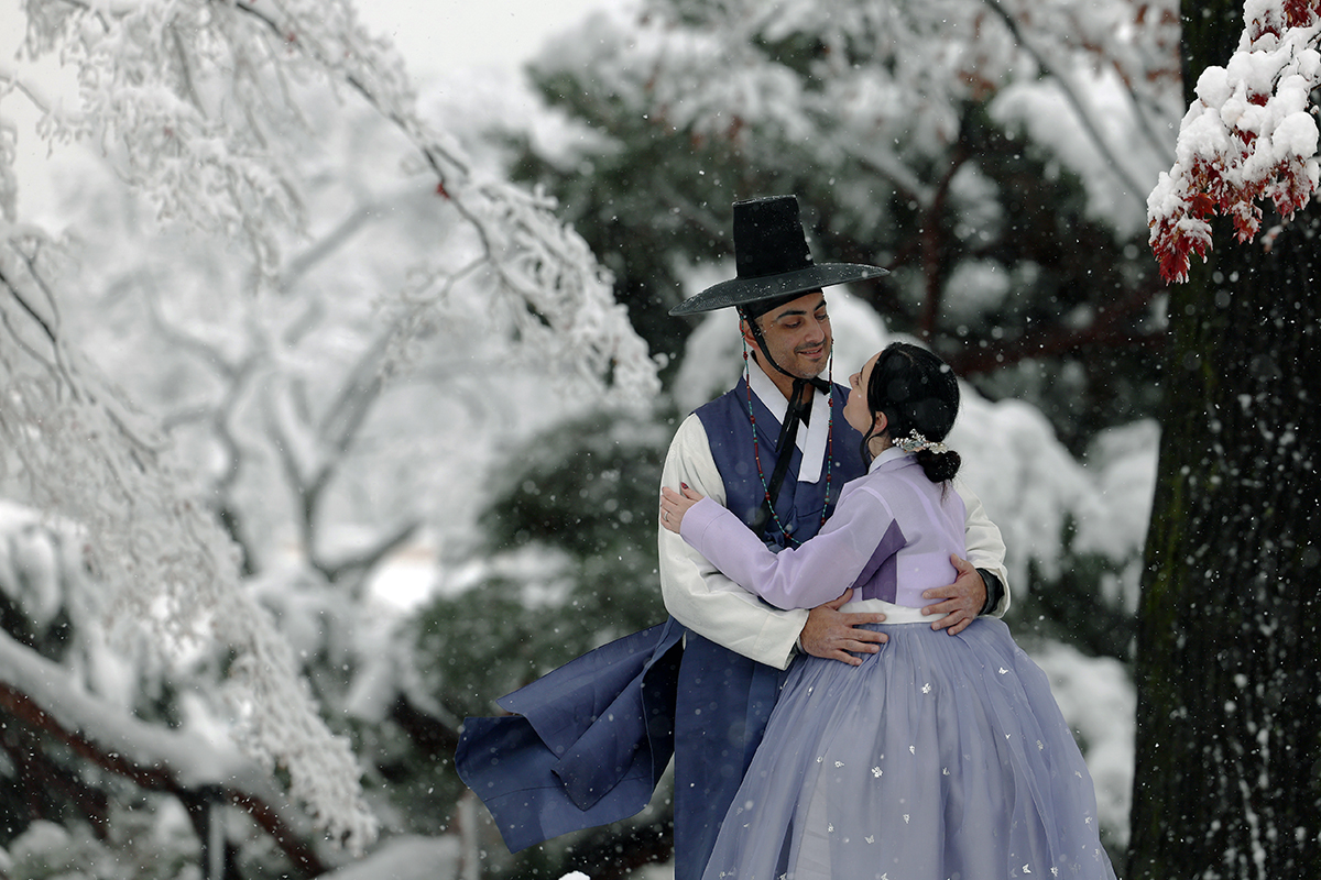 Dua orang wisatawan asing yang mengenakan hanbok terlihat sedang berfoto dengan latar belakang salju yang turun dengan deras pada tanggal 27 November 2024 di Istana Gyeongbokgung yang terletak di Jongno-gu, Seoul. (Lee Jun Young)