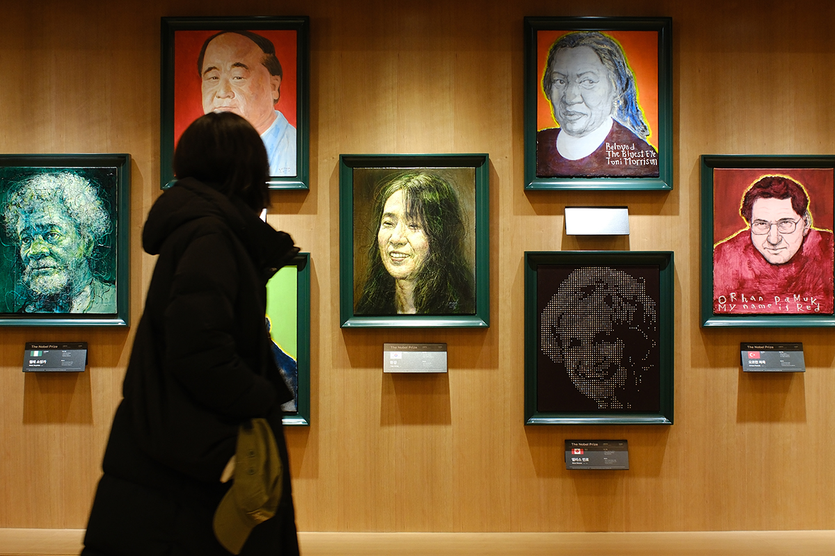 Pada tanggal 10 Desember 2024 seorang warga terlihat sedang mengamati potret Han Kang yang dipajang di ruang pameran khusus untuk para pemenang Nobel di Toko Buku Kyobo cabang Gwanghwamun di Seoul. (Yonhap News)