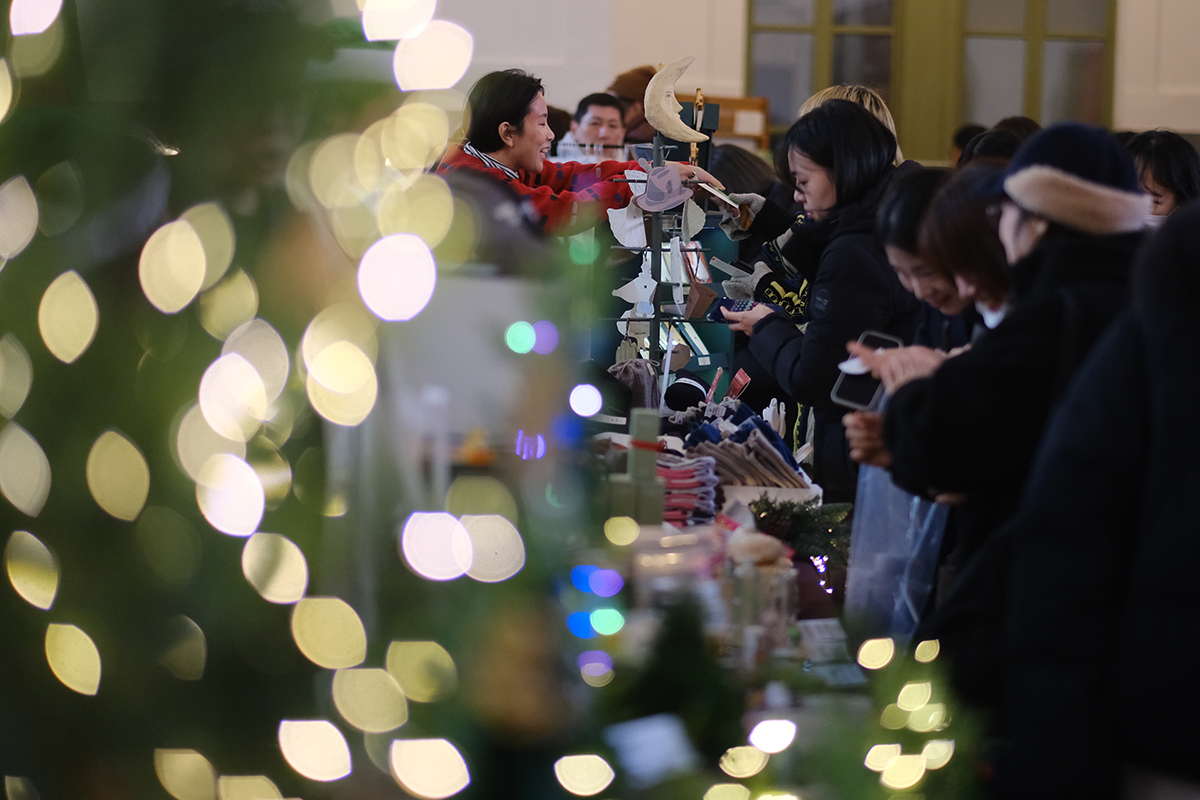 Para warga terlihat sedang memperhatikan berbagai barang pameran di Pasar Natal Rahasia yang digelar pada tanggal 20 Desember 2024 di Culture Station Seoul 284, Bongnae-dong, Jung-gu, Seoul. Lebih dari 90 buah perusahaan berpartisipasi dalam acara ini. Beragam alat tulis, perlengkapan rumah tangga, makanan, dan produk anak-anak dapat dinikmati dalam Pasar Natal Rahasia. Selain itu, terdapat juga berbagai program lainnya, seperti parade Sinterklas untuk anak-anak, pertunjukan jaz, dan acara bincang buku. (Yonhap News)